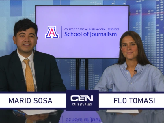 Two students sit at the anchor desk in a studio