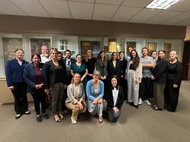 A group of visitors stands in the hallway of the School of Journalism