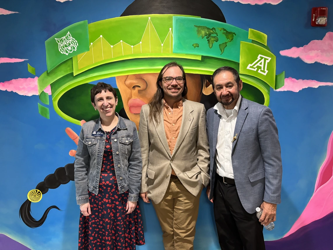 Group stands in front of mural