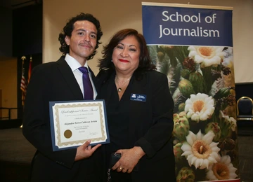 A student holding an award poses with the school director