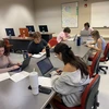Students write news stories at a desk