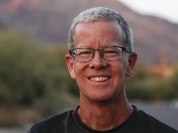 The School of Journalisms new Professor Rick Wiley poses in front of a desert landscape for a photograph.