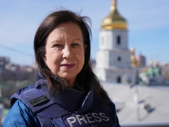 Lyse Doucet stands in front of a temple with a bullet proof vest.