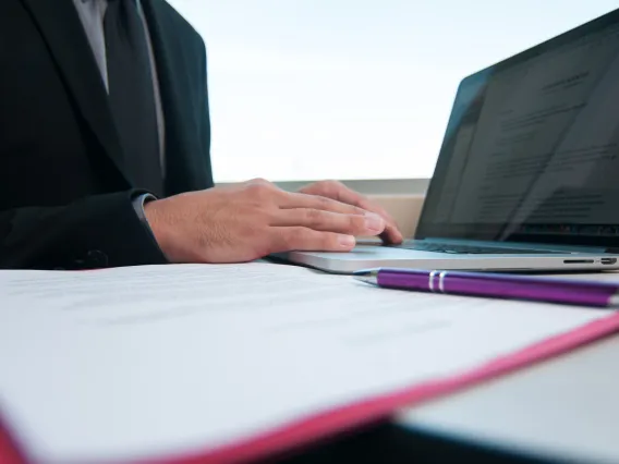 Man types at laptop with documents open