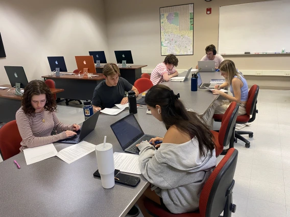 Students write news stories at a desk