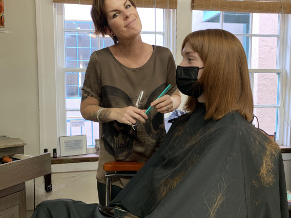 A woman cutting the hair of another woman.