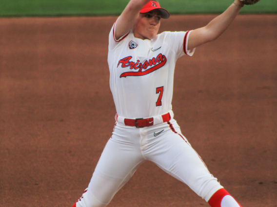 A woman pitching at a softball game.