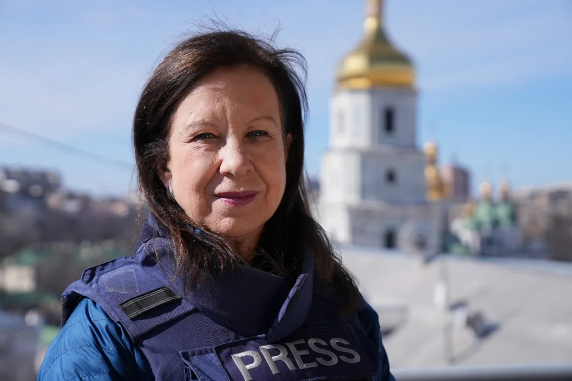 Lyse Doucet stands in front of a temple with a bullet proof vest.