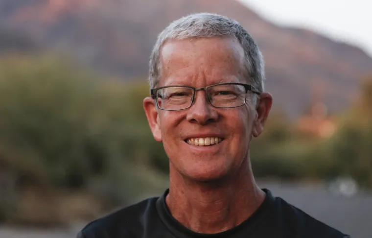 The School of Journalisms new Professor Rick Wiley poses in front of a desert landscape for a photograph.