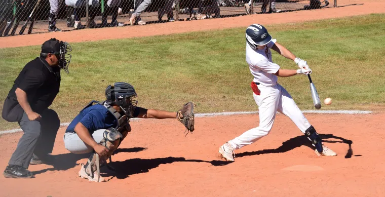 A batter swings at home plate as a baseball approaches