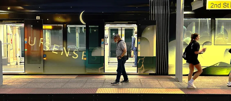 Pedestrians walk by the Sun Link streetcar