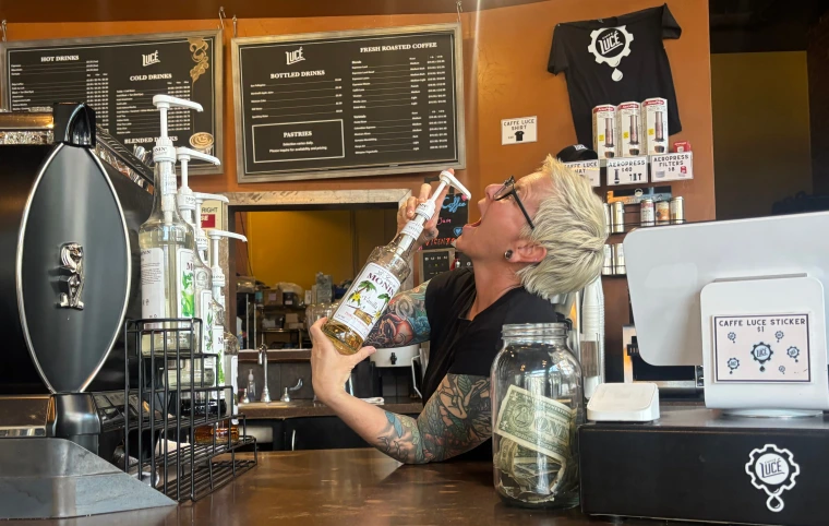 A barista poses with a bottle of syrup at Caffe Luce