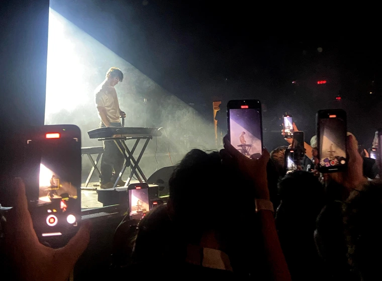 A musician stands on stage in front of a keyboard