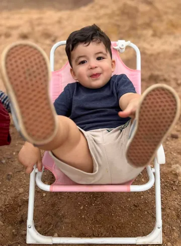 A child leans back in a chair smiling 