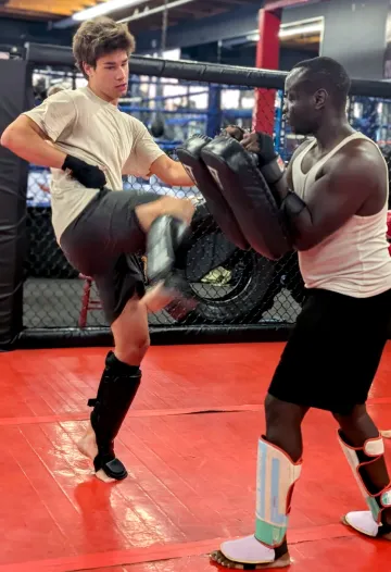 A boxer kicks the pad of another boxer