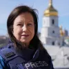 Lyse Doucet stands in front of a temple with a bullet proof vest.