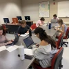 Students write news stories at a desk
